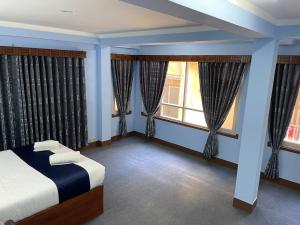 a bedroom with blue walls and windows with a bed at Andrew Home in Kathmandu