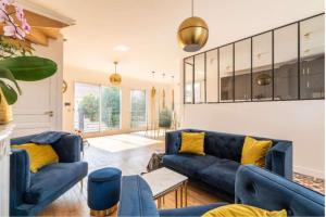 a living room with blue couches and yellow pillows at Maison avec jardin 20min de Paris in Asnières-sur-Seine