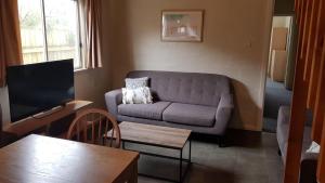 a living room with a couch and a tv at Billungar Unit 2 at Hat Head - 1 Creek Street in Hat Head