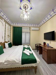 a bedroom with a large bed and a chandelier at Hotel Zarhal in Bukhara