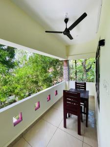 a balcony with a table and chairs and a window at Cliff & Coral in Varkala
