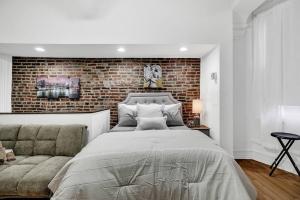 - une chambre avec un grand lit et un mur en briques dans l'établissement Uniquely Designed Metropolitan Apt In Center City, à Philadelphie