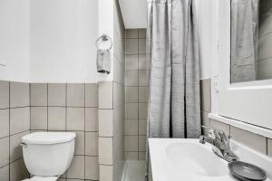 La salle de bains blanche est pourvue de toilettes et d'un lavabo. dans l'établissement Uniquely Designed Metropolitan Apt In Center City, à Philadelphie
