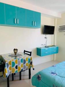 a room with a table and a tv and blue cabinets at The Persimmon Studios Tower 3 Unit 1153 located in MJ Cuenco Cebu City in Cebu City