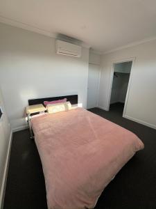 Brand new comfortable room in a beautiful suburb في St Albans: غرفة نوم بسرير كبير مع بطانية وردية