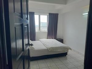 a small bedroom with a bed and a window at Globallon Services Apartment, Melaka Town Hotel in Malacca