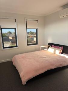 a bedroom with a large bed with three windows at Brand new comfortable room in a beautiful suburb in St Albans