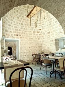 un ristorante con tavoli e sedie e un muro di mattoni di Hotel Parco delle Querce a Crispiano