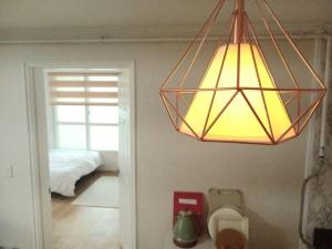 a light hanging over a room with a bed at Sarangchae Yeonsu 2 in Incheon