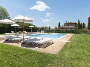 a pool with chairs and umbrellas in a yard at Luxurious apartment in Lucignano with views in Lucignano