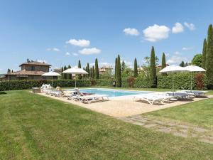a swimming pool with lounge chairs and umbrellas at Luxurious apartment in Lucignano with views in Lucignano