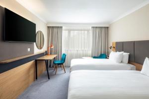 two beds in a hotel room with a desk and a tv at Holiday Inn London - Gatwick Airport, an IHG Hotel in Horley