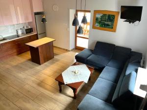 uma sala de estar com um sofá azul e uma cozinha em Agroturystyka Gajówka Pilica 