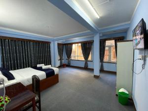 a bedroom with a bed and two windows and a tv at Andrew Home in Kathmandu