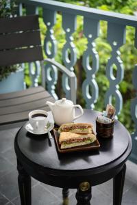 a table with a plate of sandwiches and a cup of coffee at Luangprabang D'or Boutique Hotel in Luang Prabang