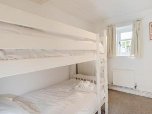 a bedroom with two bunk beds and a window at Dairy Cottage-uk45593 in Verwick