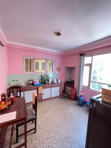 a kitchen with pink walls and a table and chairs at Andrew Home in Kathmandu