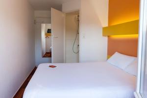 um pequeno quarto com uma cama branca e um closet em The Originals Access, Hôtel Bordeaux Lac em Bruges