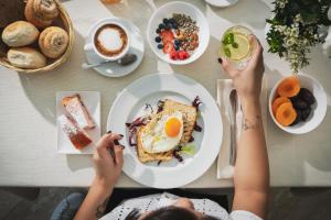 una mujer sentada en una mesa con un plato de comida para el desayuno en Hotel Ascot Riccione, en Riccione