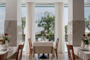 a dining room with white tables and chairs and a large window at Hotel Ascot Riccione in Riccione
