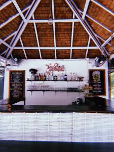 a restaurant with a bar with a menu on the wall at Tropical Hostel in Ko Phayam