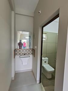 a bathroom with a toilet and a sink and a mirror at SN Residency in Kalpetta