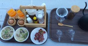 a wooden tray with food and wine glasses and plates of food at บ้านไร่นายสิงห์-Banrainaysing in Ban Huai Khai