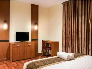 ein Hotelzimmer mit einem Bett und einem TV in der Unterkunft STEFANI MAKATI HOTEL in Pekanbaru