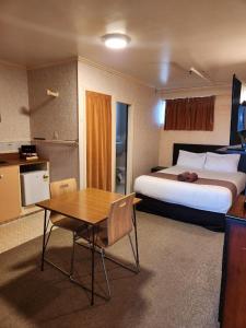 une chambre d'hôtel avec un lit, une table et une cuisine dans l'établissement Mayfair Court Motel, à Tokoroa