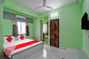 een slaapkamer met groene muren en een bed met rode kussens bij Collection O Hotel 7dayz Inn Near City Centre 2 in Calcutta