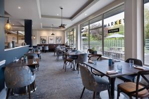 um restaurante com mesas e cadeiras de madeira e janelas em Delta Hotels by Marriott Huntingdon em Huntingdon