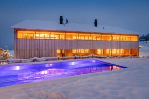 un bâtiment avec une piscine dans la neige dans l'établissement Fuchsegg Eco Lodge, à Egg