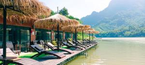 a row of chairs and umbrellas next to a body of water at Ou River House in Nongkhiaw