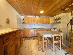 a kitchen with wooden cabinets and a table with stools at Lignod - Appartamento con 2 Camere da Letto in Champoluc