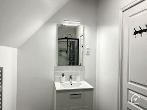 a white bathroom with a sink and a mirror at Les studios d'Elina in Châtellerault