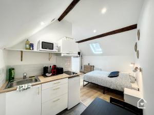 una cocina con fregadero y una cama en una habitación en Les studios d'Elina, en Châtellerault