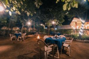 un restaurante con mesas azules y sillas por la noche en Saalwood Safari Lodge, en Dhanwār