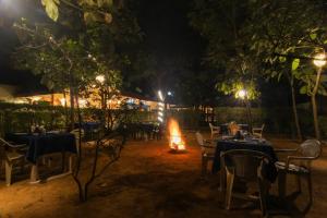 un restaurante con mesas y chimenea por la noche en Saalwood Safari Lodge, en Dhanwār