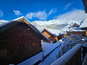 a log cabin in the snow with mountains in the background at Chalet au pied des pistes in Saint-François-Longchamp