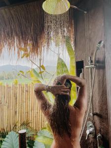 a man is taking a shower in a bathroom at Desa Cabins in Balian