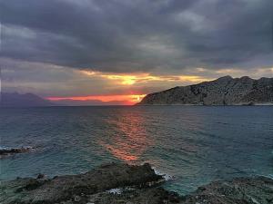 a sunset over the ocean with mountains in the background at La Bandolaise à Perdika in Perdika