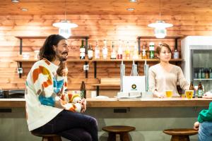 a man sitting at a bar talking to a woman at Ten to Ten Hostel in Sapporo