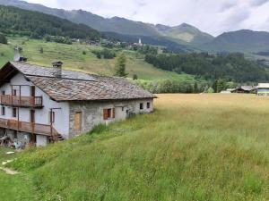 an old house on a hill in a field at The Snow - Appartamento Panoramico con Balcone in Champoluc