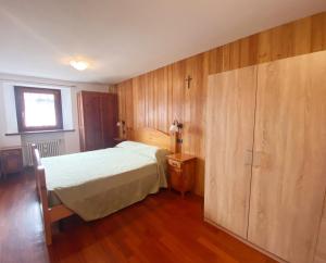 a bedroom with a bed and a wooden wall at The Snow - Appartamento Panoramico con Balcone in Champoluc