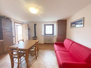 a living room with a red couch and a table at The Snow - Appartamento Panoramico con Balcone in Champoluc