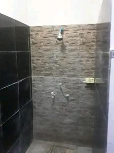 y baño con ducha y pared de piedra. en Creative Homestay, en Gili Trawangan