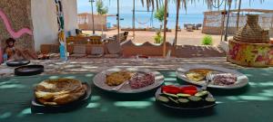 een tafel met borden eten op een tafel vlakbij het strand bij Michael's House in Nuweiba