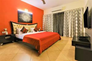 - une chambre avec un lit aux murs orange et une télévision dans l'établissement La Goa Villa - 4BHK, Baga, à Baga