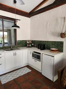 a kitchen with white cabinets and a sink at The Lavender Patch in Mundaring
