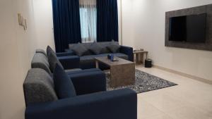 a living room with blue couches and a tv at Mabeet Al-Khobar in Al Khobar